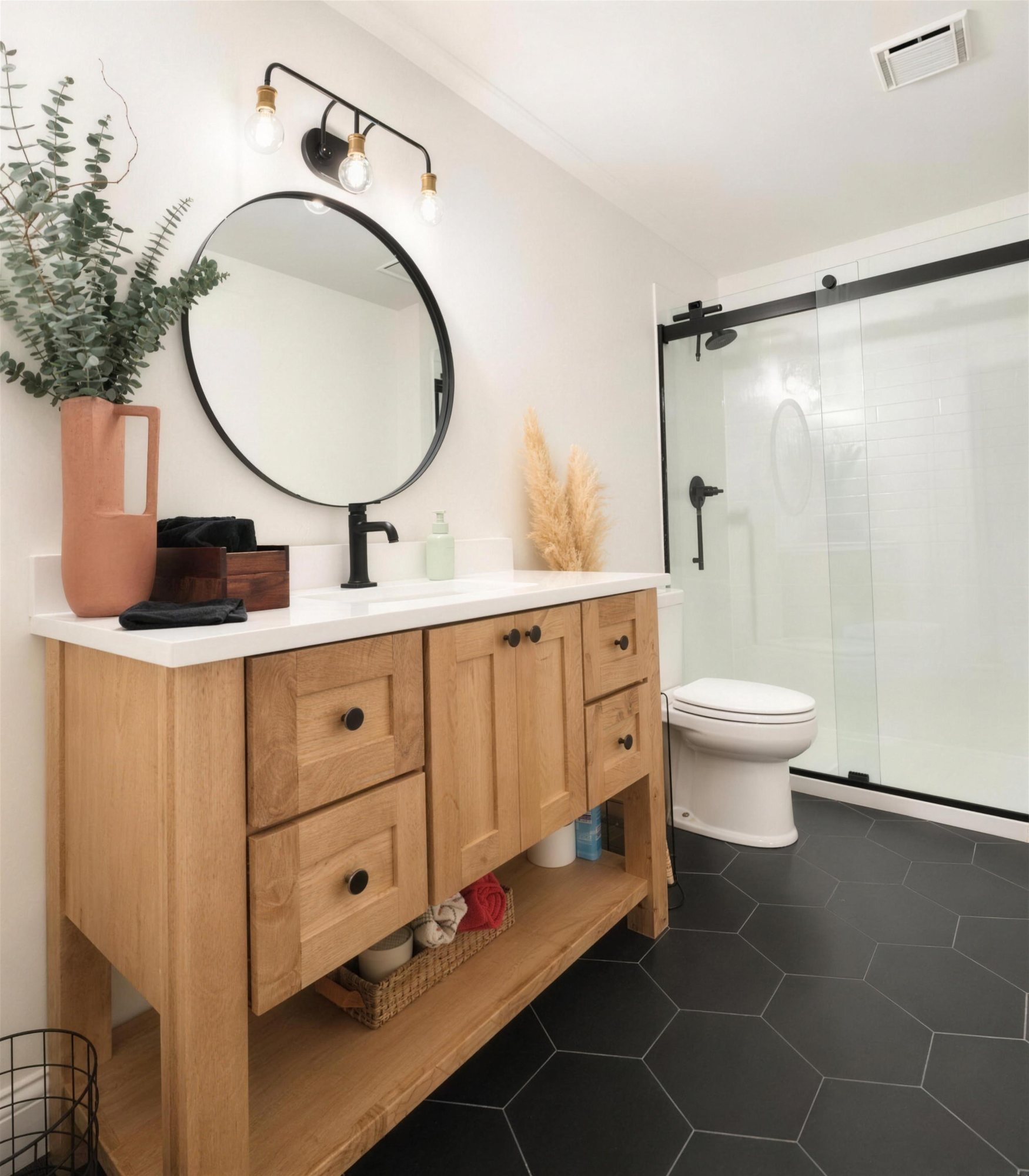Bathroom design illustration with a natural wood vanity, black hardware, a round mirror, a black hexagon tile floor, and a glass sliding shower